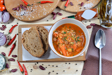 Kharcho soup in a white plate on a wooden board on a table with food decor