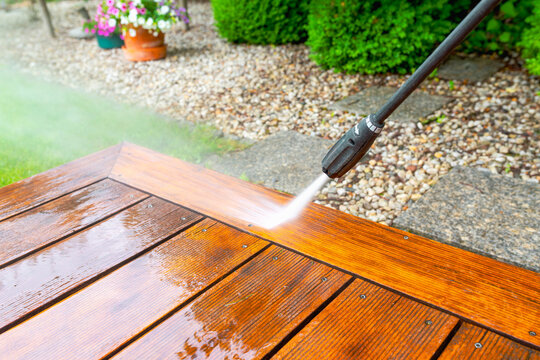 cleaning terrace with a power washer - high water pressure cleaner on wooden terrace surface