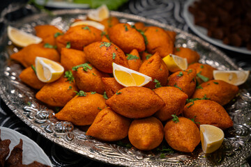 Traditional Turkish and Arap icli kofte served with lemon wedges on silver tray. Golden fried stuffed bulgur meatballs kibbeh. Popular dish in Middle Eastern cuisine. Dinner concept
