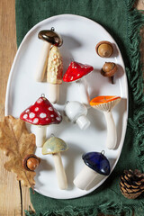 Ceramic mushrooms, pine cones, and acorns on a ceramic plate and wooden tabletop.