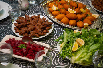 Plate of traditional cig kofte served with beet salad, greens and lemon slices. Traditional middle eastern and turkish cuisine kibbeh. Spicy bulgur raw meatballs. Table dinner concept