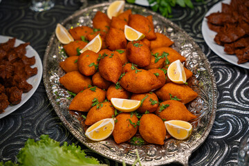 Traditional Turkish and Arap icli kofte served with lemon wedges on silver tray. Golden fried stuffed bulgur meatballs kibbeh. Popular dish in Middle Eastern cuisine. Dinner concept