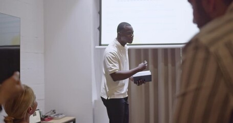 Multiracial business team attending a presentation in a modern office. A diverse group of colleagues gather for a business meeting or training session.