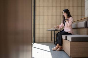 Businesswoman talking on phone and reading notes in modern office