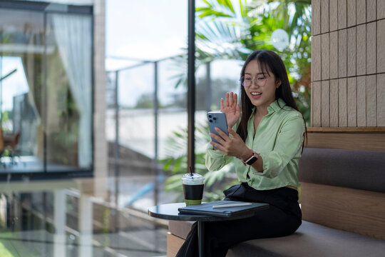 Businesswoman video calling and waving in cafe