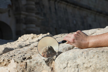 Archaeologist using a magnifying glass to study a relic among the remnants of an ancient city....