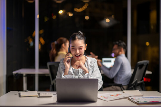 Businesswoman talking on phone and working late at office
