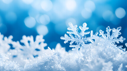 Delicate snowflakes rest on soft bed of snow against dreamy blue bokeh background, evoking serene winter atmosphere