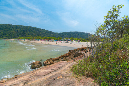 Guaiuba Beach, Guaruja SP, Brazil. Sunny day over the small bay with tranquil sea. Image of leisure and tourism on the Sao Paulo coast. Hills covered in Mata Atlantica vegetation frame the view.