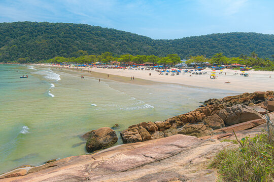 Guaiuba Beach, Guaruja SP, Brazil. Sunny day over the small bay with tranquil sea. Image of leisure and tourism on the Sao Paulo coast. Hills covered in Mata Atlantica vegetation frame the view.