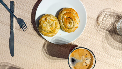 Golden spiraled pastries whisper warmth beside a foamy espresso, echoing cozy Nordic Fika and Pi Day indulgence