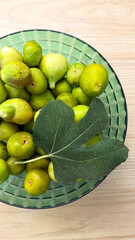 Bowl of verdant figs and singular leaf, Evoking Lammas harvest and Mediterranean culinary alchemy, rustic autumn bounty captured