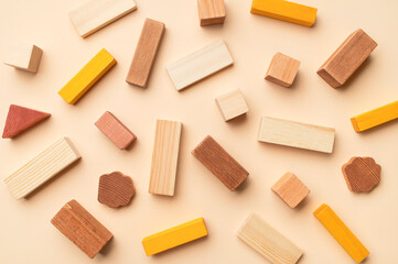 Wooden children's construction set blocks of different shapes natural colors on beige background. Montessori style cubes game for toddlers flat lay top view. Concept of learning and education