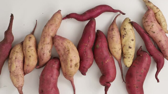 overhead view of uncooked sweet potatoes light surface