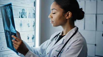 female doctor examining x-ray image, medical professional in white coat with stethoscope, bright hospital interior, confident healthcare worker smiling while analyzing radiology scan - Powered by Adobe