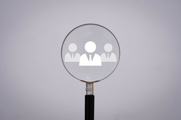 Magnifying glass focusing on business team icon, representing recruitment, HR, employee selection, or leadership. Perfect for human resources, hiring, and management concepts.