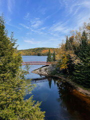 Fototapeta premium Autumn view of a bridge over a lake in the forest. Algonquin Park, Canada. 