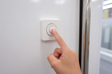 Naklejka premium Close up of hand pressing white button to open subway doors, modern public transportation, clean environment, urban travel, convenience, safety, anticipation