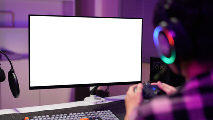 Man in dimly lit home playing video games on isolated screen gaming PC at computer desk, enjoying day off from work. Gamer battling enemies in online multiplayer shooter on mockup display © Stella 16