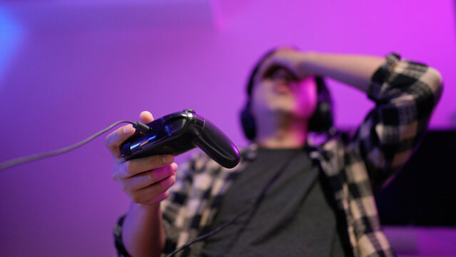 Emotional angry mad furious talking in microphone video game loss addiction asian guy male man streamer gamer wearing headphones playing virtual battle lost fail internet computer at night home