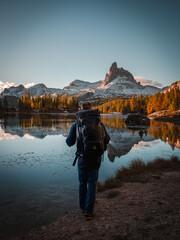 Hiker is standing at mountain lake federa in the dolomites at sunrise in autumn