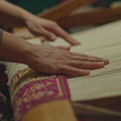 Obraz premium The hands of a weaver are carefully working on a loom, creating a beautiful textile with intricate patterns.