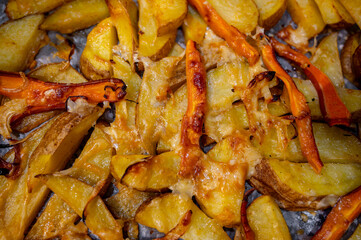 Roasted Potato Pieces with Cheese and Carrots on Baking Tray