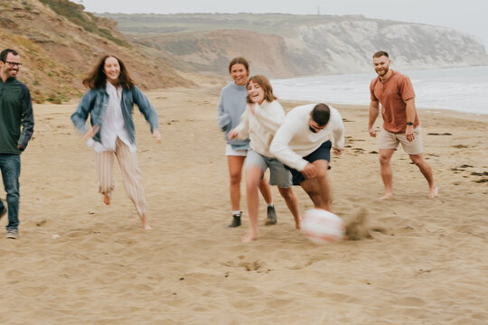 A group of people playing beach soccer. Scene is fun and energetic. The group is enjoying their time together and engaging in a physical activity