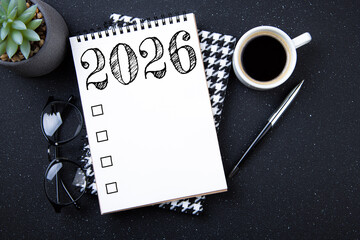 New year goals 2026 on desk. 2026 resolutions list with notebook, plant on black table. Resolutions, plan, goals, action, checklist, idea concept. New Year 2026 resolutions, copy space