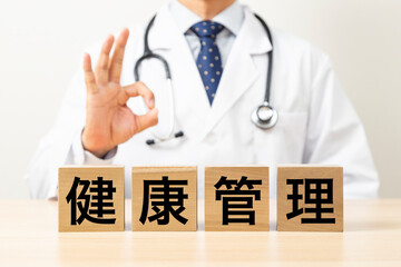 「健康管理」と書かれたブロックとOKサインをする医師
