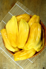 Fresh yellow jackfruit bulbs in a wooden bowl