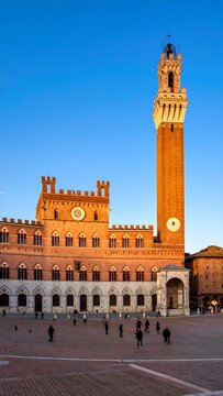 A majestic brick building and towering clock-tower set against a blue sky