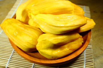 Fresh yellow jackfruit bulbs in a wooden bowl