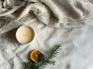 Minimal holiday flat lay, white ceramic candle holder with beeswax candle, natural fir sprig and dried orange slice, neutral beige palette, Scandinavian style