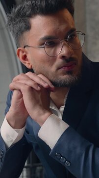 Pensive doubtful Hindu business man serious businessman thinking with laptop Indian millennial professional guy male pondering computer task at table brainstorm decide searching inspiration in office