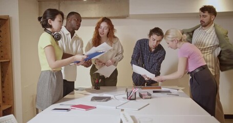 International business team collaborates on a project in a startup office, reviewing documents and discussing strategies. - Powered by Adobe