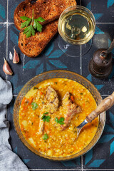 Lentil soup with pork and vegetables, served with white wine and croutons.