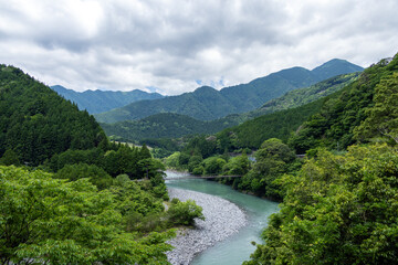 深い緑の山間にエメラルドグリーンの水が流れる大井川の清流