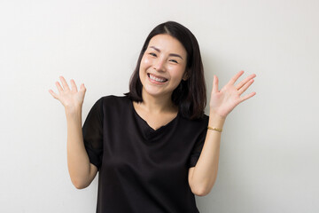 Happy young Asian woman with a beautiful smile, raising her hands in excitement or surprise. Isolated on a white background studio portrait with copy space for advertising.