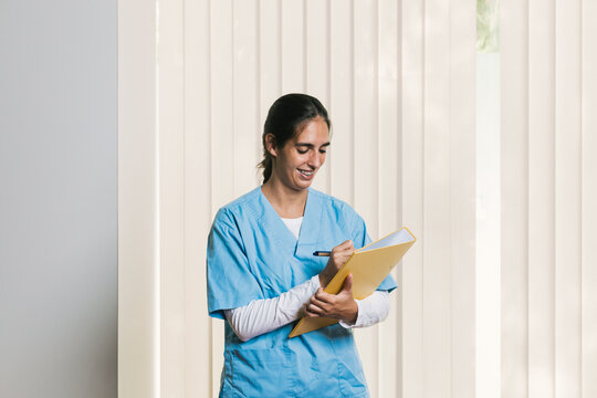 Physiotherapist writing notes on patient's medical record in rehabilitation clinic