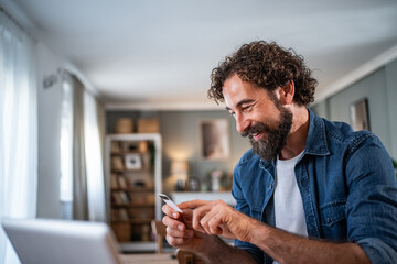 Fototapeta premium Man using credit card for online payment at home
