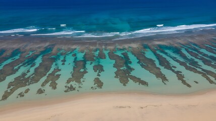 Aerial view of coastal beach with rippling sand patterns and ocean waves