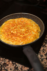 Potatoes, onion and eggs frying on pan. Spanish cuisine. Cooking delicious spanish omelette at home.