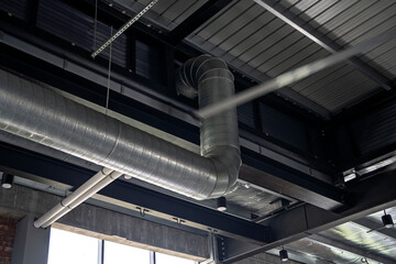 Close-up view of a metallic air duct ventilation system installed along the ceiling of a modern...