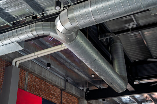 Close-up view of a metallic air duct ventilation system installed along the ceiling of a modern industrial-style building.
