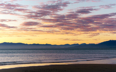 Pink clouds paint the sky over mountains
