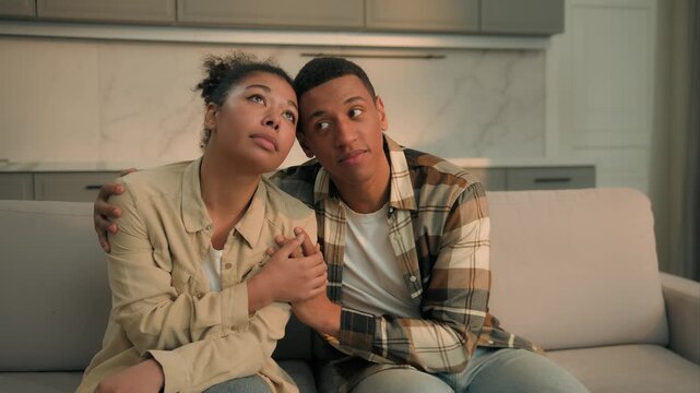 Stressed African American married couple upset cuddling feeling disappointed sad family man woman hugging suffering unwanted pregnancy trouble relocating home eviction money bankruptcy selling house