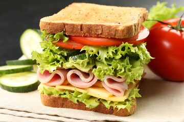 Tasty sandwich with ham, cheese and vegetables on table, closeup