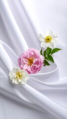 Arrangement of flowers, pink and white, on softly draped, white fabric