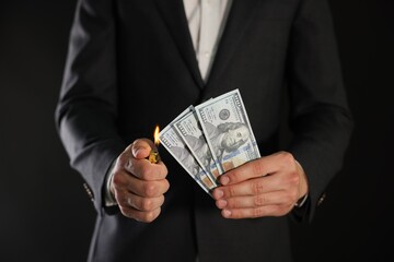 Man burning dollar banknotes on black background, closeup